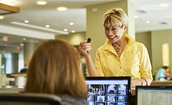 Resident at receptionist desk holding a key FOB
