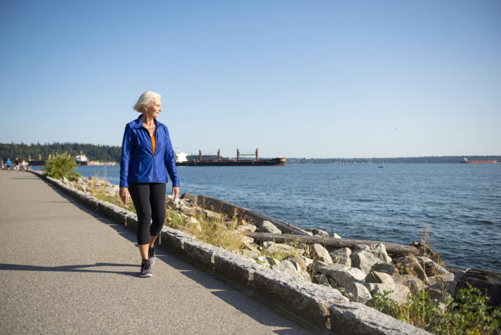 Senior woman walking along seawall