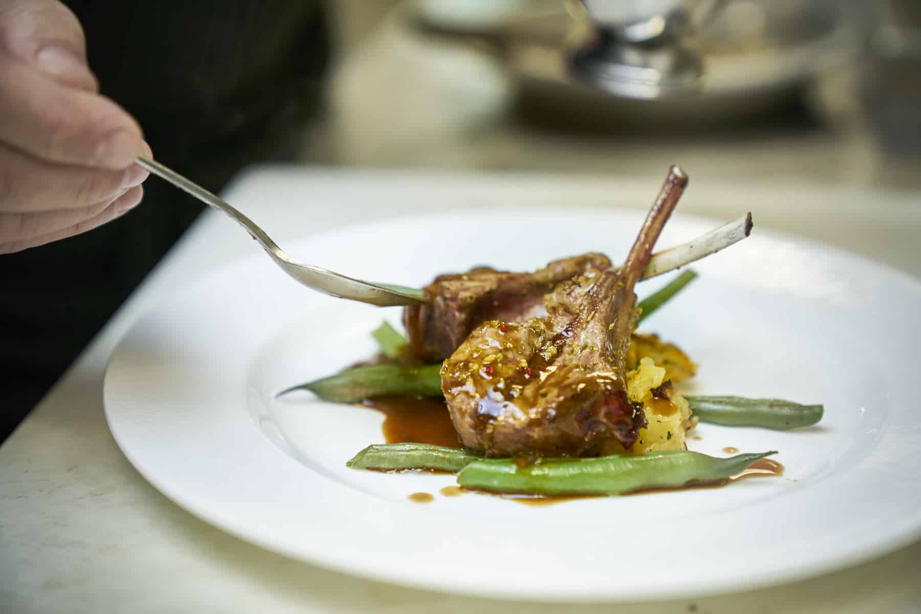 A chef-prepared meal on a plate being garnished by the chef. Independent Retirement Community.