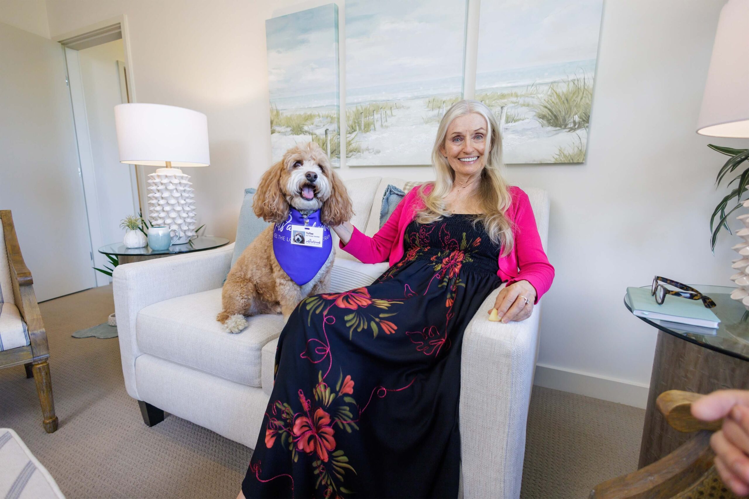 A female senior resident wearing a long dress sitting down with her puppy. Best Years. Independent Retirement Community.