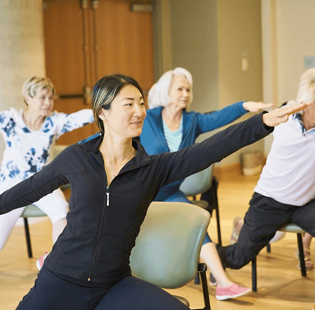 An instructor and three residents participating in a fitness class