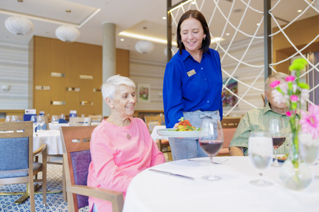 Oceana PARC Dining Room manager serves resident beautifully plated meal.